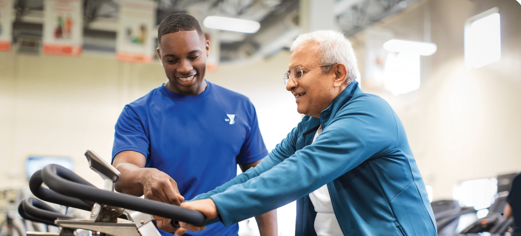 YMCA trainer showing older member how to use spin bike