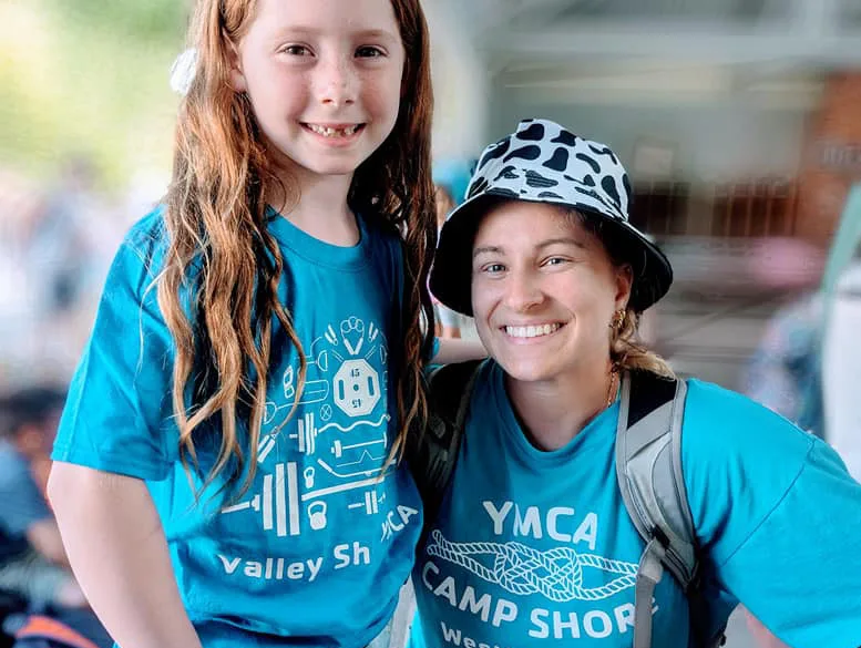 A student of our childcare programs smiles with their certified instructor at YMCA Camp Shore